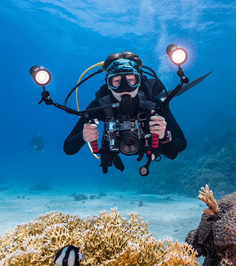 Underwater photographer capturing coral reef scene.