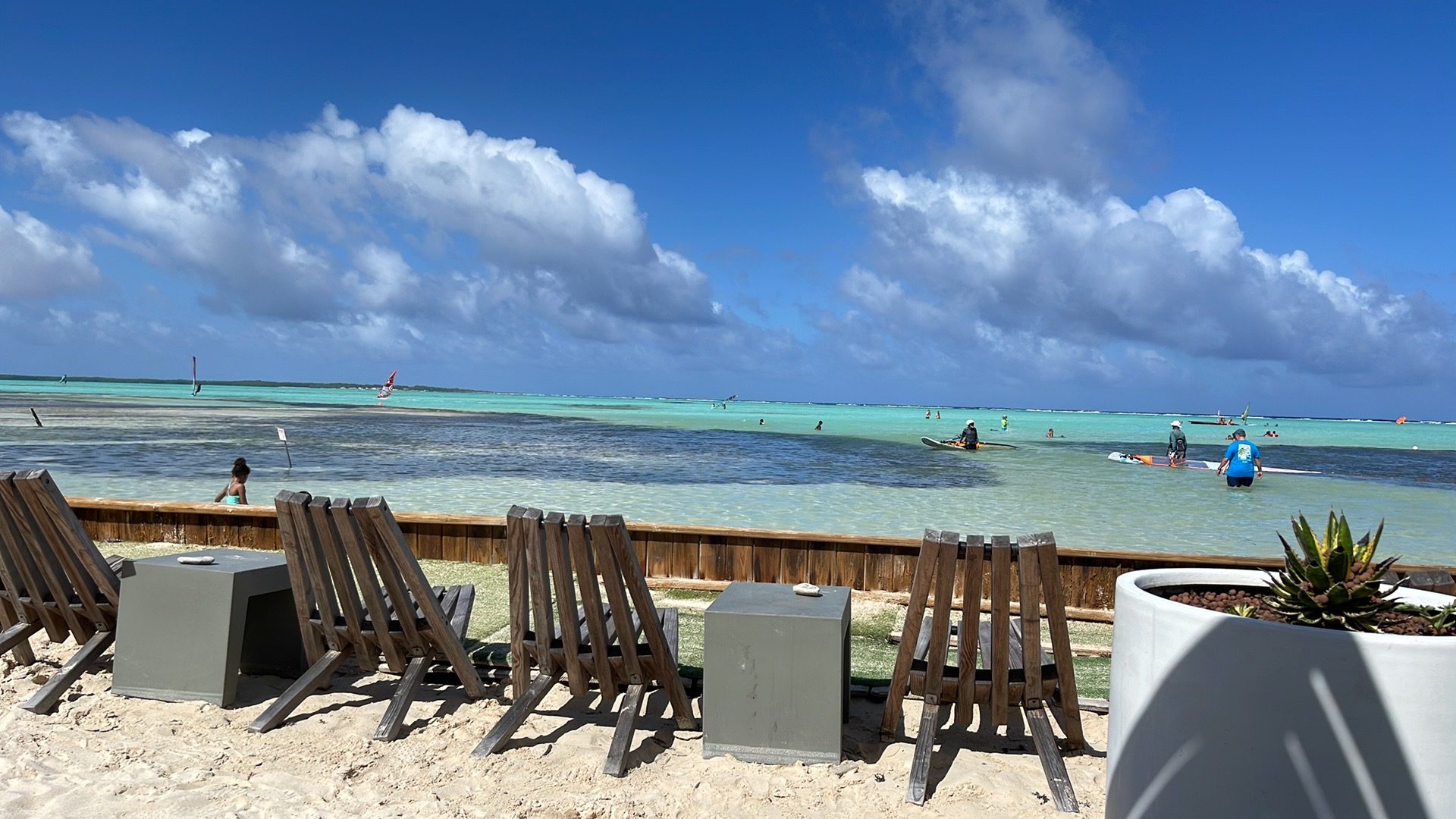 Beach chairs facing turquoise ocean under clouds.